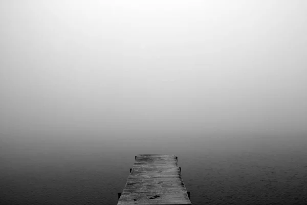 Die Brücke, die sich in den nebligen See erstreckt — Stockfoto