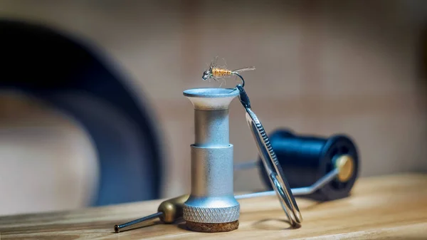 Mosca vuela sobre un fondo de herramientas para tejer. Pesca con mosca . — Foto de Stock