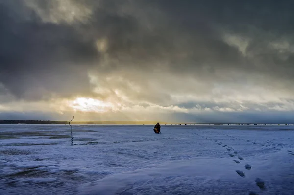 Fisherman on a background of storm clouds. Winter ice fishing on — 스톡 사진