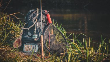 Nehir kıyısında olta kamışı, sırt çantası ve olta takımı. Tenkara.