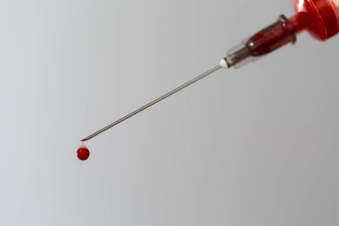 Kan örneğiyle birlikte şırınga. İğnenin ucunda bir damla kan var. Kan kimyası. Virüsler için kan testi.