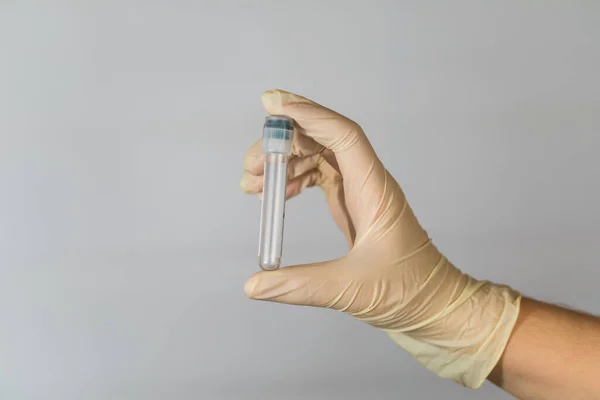 Tube à essai vide pour l'analyse des biomatériaux entre les mains d'une infirmière. Analyse clinique des virus avec mesures de précaution . — Photo