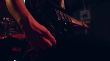 Gitaristlerin ellerini kapayarak elektro gitara ses kablosu takar ve ses ve ton düğmelerini ayarlar
