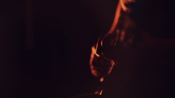 Adam oturmuş ve karanlık bir odada gitar çalmak — Stok video