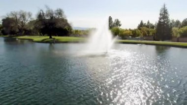 Golf sahasının lüks bir havuz köşkünden bir manzara, yeşil çimlerin üzerinde küçük bir göl