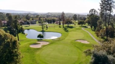 Golf sahasının lüks bir havuz köşkünden bir manzara, yeşil çimlerin üzerinde küçük bir göl