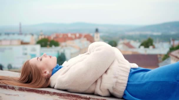 身穿白色生态皮毛的年轻女子躺在屋顶上 — 图库视频影像