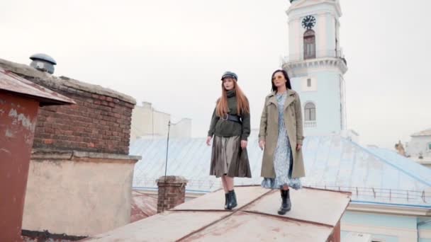 Wspaniałe szczupłe dziewczyny w ubraniach mody spacerujące po dachach budynków miejskich — Wideo stockowe