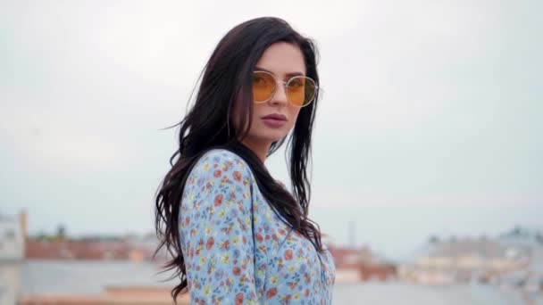 Young girl in blue dress and yellow sunglasses posing as a model for the photo shoot on the roof — ストック動画