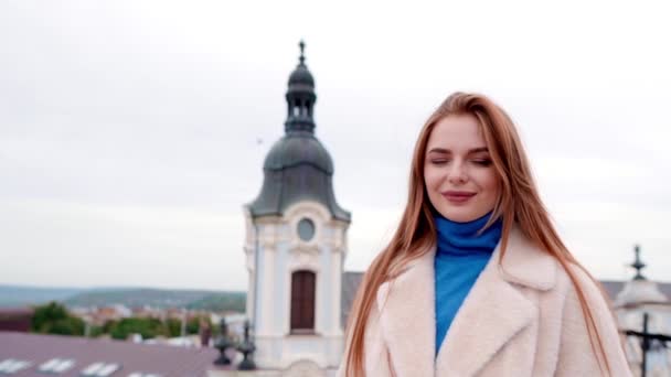 Menina em um casaco de pele eco branco posando contra o pano de fundo da cidade — Vídeo de Stock