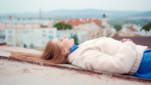 Giovane donna in eco pelliccia bianca posa sdraiata sul tetto — Video Stock