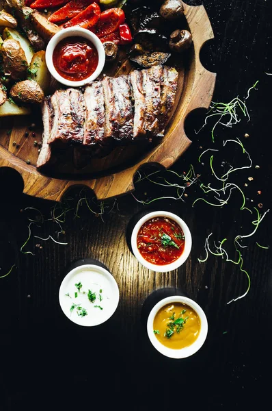 Tereyağlı sebzeli kaburga, ahşap tahtada barbekü sosu ve masa.