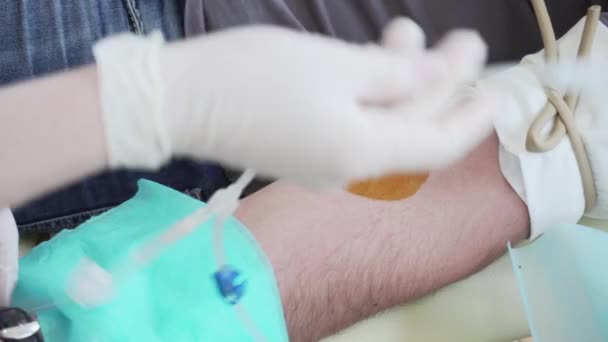 Donneur donnant du sang, l'infirmière poignarde l'aiguille dans la veine du donneur, pompant le sang. — Video