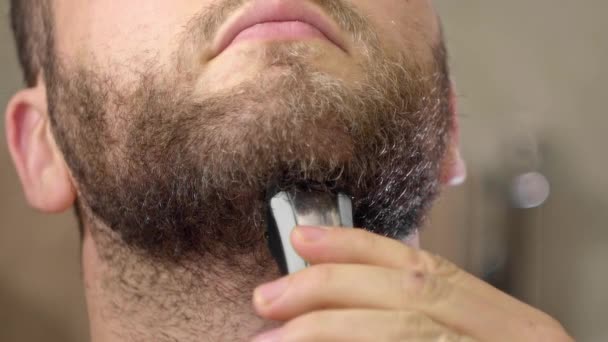 Barba afeitado en seco utilizando la máquina de recorte eléctrico. Hombre adulto barba afeitándose de cerca. Vista frontal — Vídeo de stock