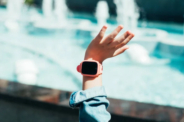 Hand of a child with pink smart watch