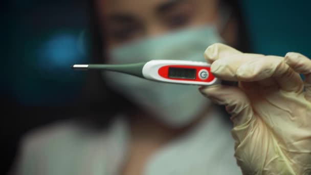 Close up of young woman doctor holding electronic thermometer — Stock Video