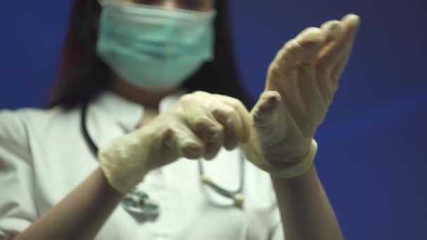 Doctora poniéndose guantes quirúrgicos esterilizados de color rosa. Mujer con uniforme médico usando guantes de látex antes del procedimiento. Preparación para el tratamiento quirúrgico en la clínica. Esteticista preparándose para trabajar. 4 k — Vídeos de Stock