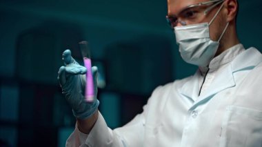 Test tüpünde bulunan sıvı örneklerini inceleyen genç bir adam.