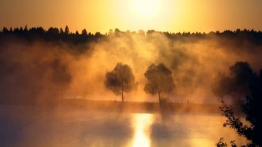 Gölde ya da nehirde turuncu gün doğumu, gün doğumunda sabah sisi. Güneşin turuncu ışınları nehirdeki sabah sisinin içinden