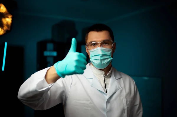 doctor with medical face mask and medical gloves shows thumb up