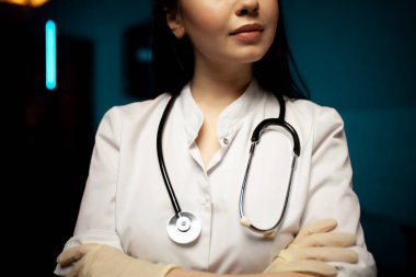 Koyu mavi arka planda elleri çapraz kesişen neşeli doktor.