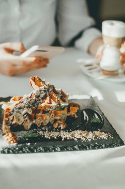 Kremalı büyük porsiyon Viyana gofretleri, bir tabağın üzerindeki çikolata şurubu bir sokak kafesinin üstünde, yakın plan.