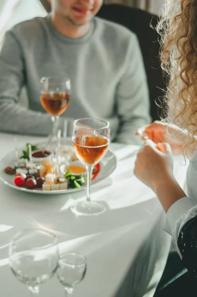 Sevgililer Günü 'nde bir çift için romantik bir akşam yemeği iki bardak soğuk beyaz şarap ve gurme Fransız peyniri tabağı.