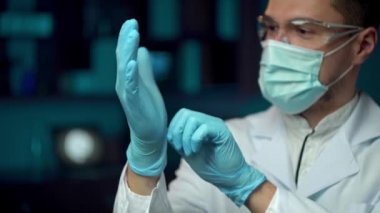 Maskeli bir laboratuvar çalışanı laboratuarlarda çalışmak için koruyucu gözlük takıyor..