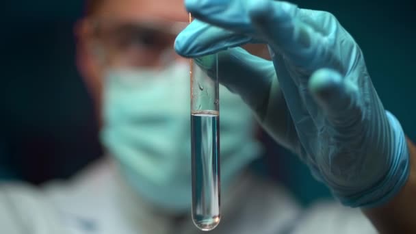 Вчений вливає хімічну речовину в пробірку, спостерігаючи реакцію — стокове відео