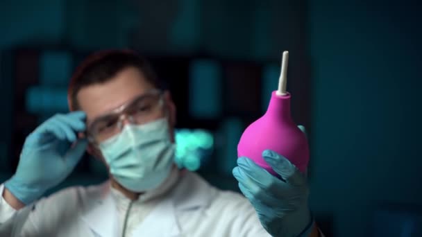 Arzt mit Klistier in einem Labor. Ein Arzt in medizinischer Maske hält einen Klistier — Stockvideo