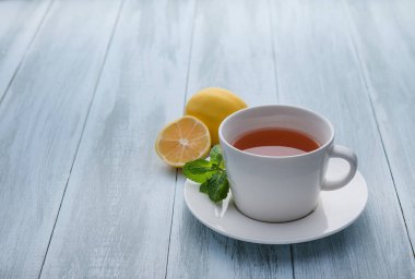 Bir fincan limonlu çay ve ahşap mavi arka planda nane. Yakın çekim