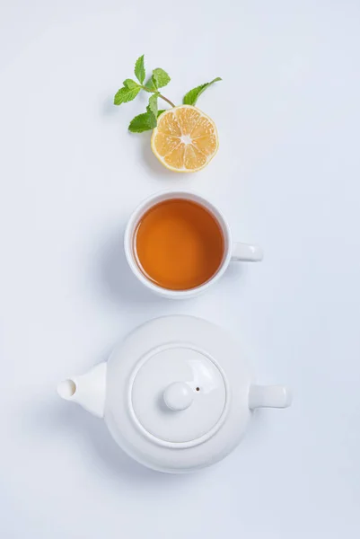 Cup of tea and teapot with lemon and mint on  white background. — Stock Photo, Image