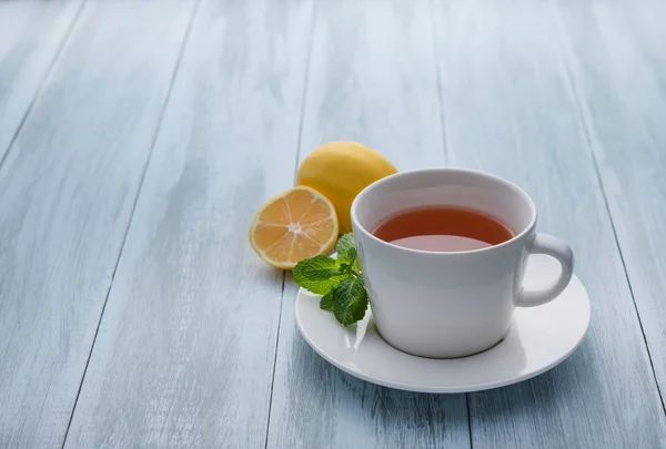 Bir fincan limonlu çay ve ahşap mavi arka planda nane. Yakın çekim — Stok fotoğraf