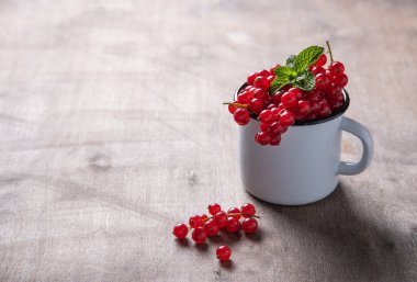 Kahverengi ahşap arka planda naneli taze kırmızı frenk üzümü.
