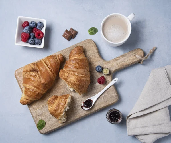 Two fresh  croissants on a cutting Board and a grey napkin — 스톡 사진