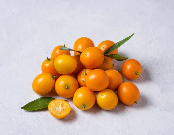 Vários kumquats doces frescos suculentos estão em uma mesa de madeira cinza — Fotografia de Stock