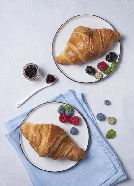 Fresh  croissant on a white plate and a blue napkin with berries — 스톡 사진