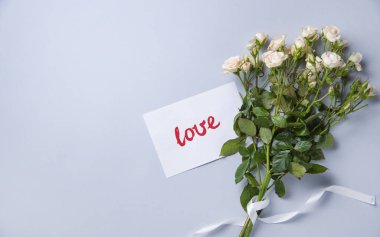 Mavi arka planda beyaz güllerden oluşan narin bir buket yatıyor. 