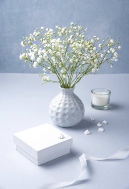 Gri bir vazoda narin bir buket beyaz jipila var. 