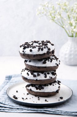 Beyaz bir zemin üzerinde beyaz bir tabakta yığılmış lezzetli taze siyah ve beyaz çörekler ve çingene çiçekleri.. 