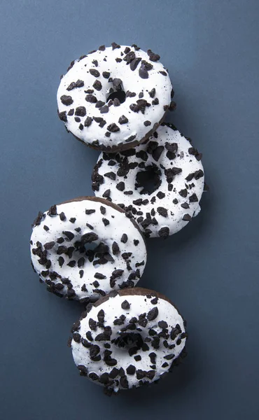 several delicious fresh hearty black and white doughnuts lie on gray background