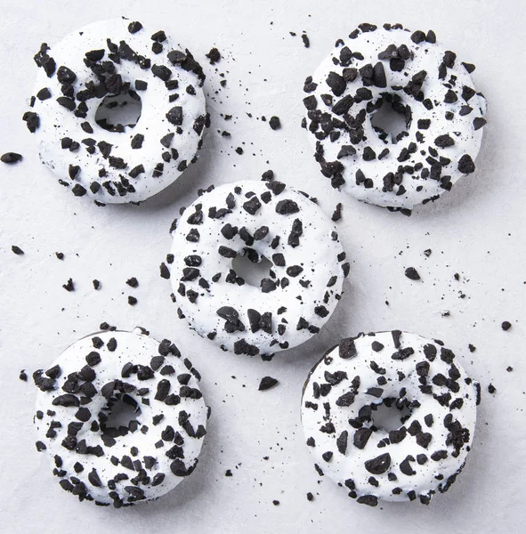 Varias deliciosas rosquillas frescas abundantes en blanco y negro yacen sobre fondo blanco — Foto de Stock
