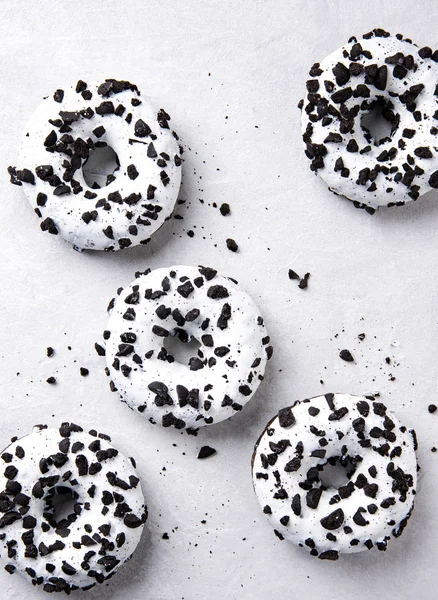 Varios deliciosos y abundantes donuts blancos y negros se encuentran sobre un fondo blanco . — Foto de Stock
