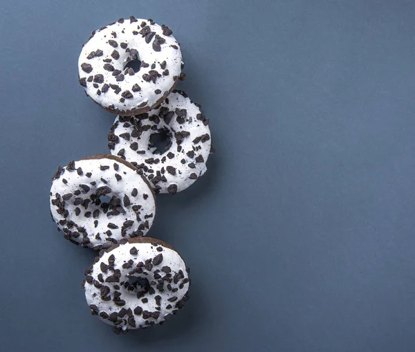 Varias deliciosas rosquillas frescas abundantes en blanco y negro se encuentran sobre un fondo gris-azul — Foto de Stock