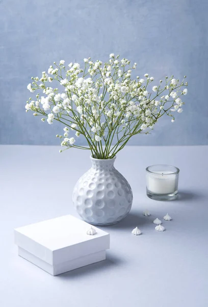 Delicato bouquet di gipsofila bianca è in un vaso grigio con candela bianca — Foto Stock