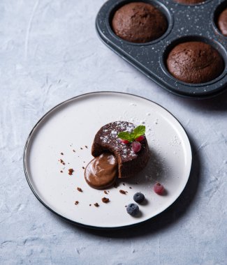 Taze sıcak vejetaryen çikolatalı lavlar ve beyaz tabakta böğürtlen.