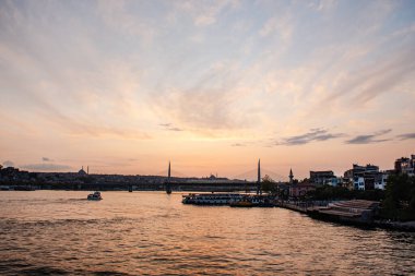 Yazın İstanbul 'da gün batımında güneşli bir manzara. Mavi camiyi gören Boğaz 'ı geçerek. Köprünün altından turistlerle dolu bir gemi geçiyor