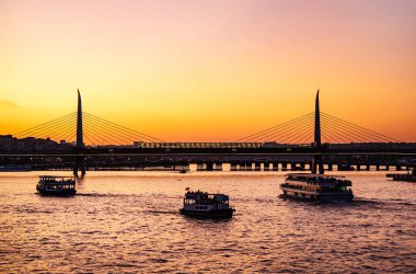 Yazın İstanbul 'da gün batımında güneşli bir manzara. Mavi camiyi gören Boğaz 'ı geçerek. Köprünün altından turistlerle dolu bir gemi geçiyor