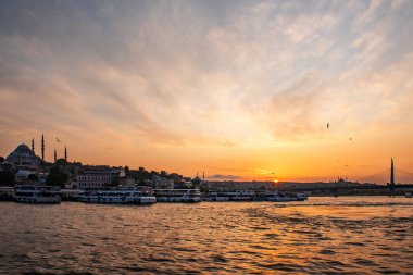 Yazın İstanbul 'da gün batımında güneşli bir manzara. Mavi camiyi gören Boğaz 'ı geçerek. Köprünün altından turistlerle dolu bir gemi geçiyor