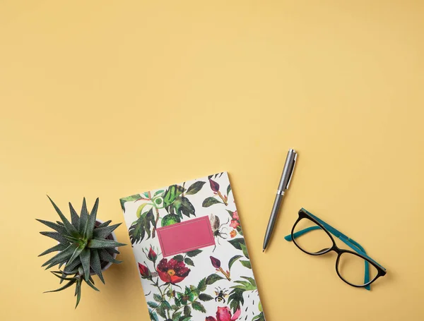 Home work. Business flat lay with  note, pencil, eye glasses and succulent  on yellow background. Image top view, flat lay and copy space